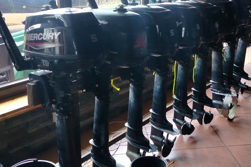 Rząd silników zaburtowych na stojakach serwisowych w warsztacie w Giżycku